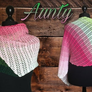 May include: A green, white, and pink crocheted shawl with the word "Aunty" written in cursive above it.