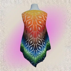 Puede incluir: Un chal de ganchillo colorido con un patrón de diamantes. El chal está hecho con un hilo degradado que pasa del amarillo al naranja, al rojo, al marrón, al azul, al verde y al negro.