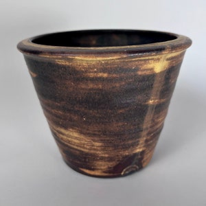 May include: A brown and yellow ceramic planter with a textured surface.