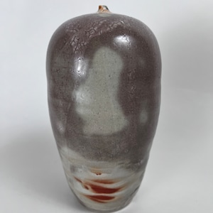 May include: A ceramic vase with a brown and white glaze. The vase has a rounded shape and a textured surface.
