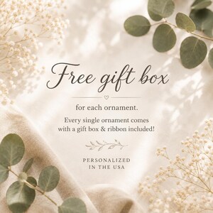 May include: A beige background with green eucalyptus leaves and white baby's breath flowers featuring text that reads: Free gift box for each ornament. Every single ornament comes with a gift box & ribbon included! PERSONALIZED IN THE USA.