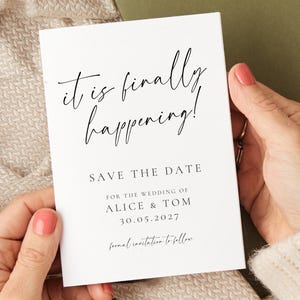 May include: A white card with the text "it is finally happening!" in elegant script, announcing a wedding. The card also includes the names Alice & Tom, the date 30.05.2027, and "Save the Date".