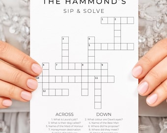 May include: A white card with a crossword puzzle titled "THE HAMMOND'S SIP & SOLVE" is held by a person. The crossword has clues listed below. The person is wearing a gold ring. The background is a light grey, textured fabric.