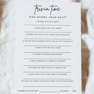 May include: A white card with the text "Trivia Time" in a handwritten font. The card includes questions like "Where did they meet?" and "Who said I love you first?" for a game. The bottom has space for a score.
