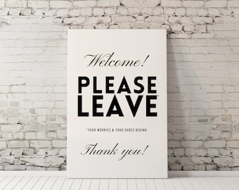 May include: White sign with black text that reads "Welcome! Please Leave *Your Worries & Your Shoes Behind. Thank you!"