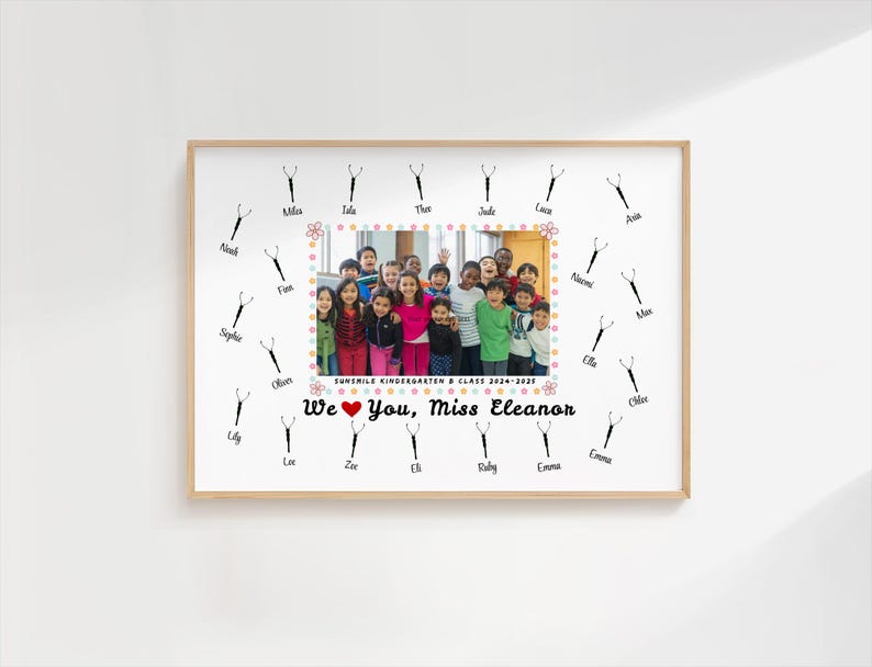 May include: A framed print featuring a group photo of children, surrounded by decorative scissors and names. The text "We love you, Miss Eleanor" is displayed below the photo. The frame is a light wood color.