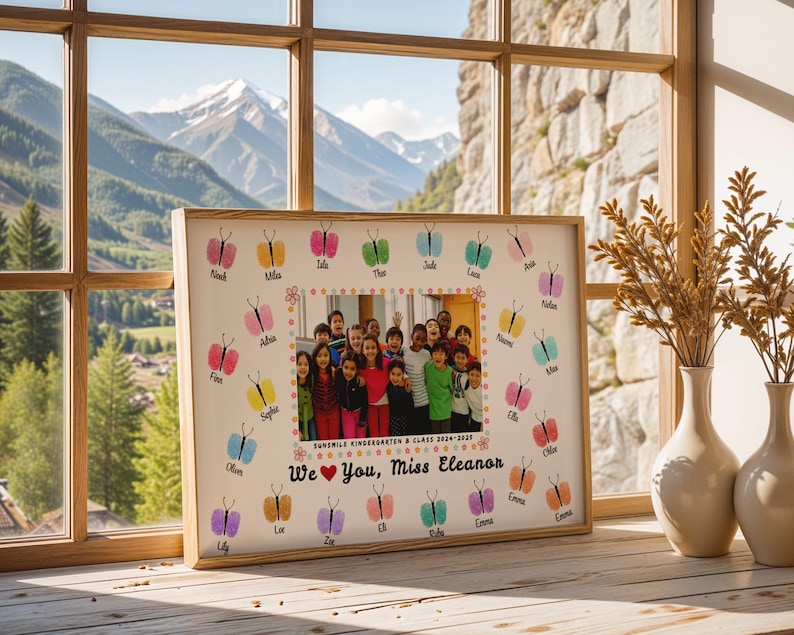 May include: A framed class photo with a light wood frame. The photo is surrounded by colorful butterfly prints with student names. The text reads "Sunshine Kindergarten & Class 2024-2025" and "We ❤️ You, Miss Eleanor."