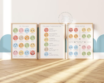 May include: Three framed prints with a light wood finish. The prints feature colorful illustrations of smiley faces representing different emotions. Text on the prints includes "My Feelings," "Feelings Thermometer," and "Mood Meter."