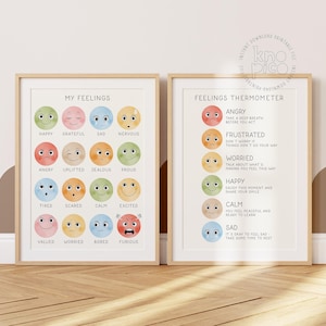 Op de afbeelding: Twee ingelijste prints met licht houten frames. De linkerprint zegt "MY FEELINGS" en toont kleurrijke emoji-gezichten die verschillende emoties vertegenwoordigen. De rechterprint is een "FEELINGS THERMOMETER".