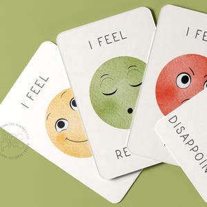 May include: A collection of emotion cards with watercolor illustrations. Each card features a different emotion, such as happy, relaxed, and disappointed, represented by a colorful face and the words "I FEEL" or the emotion's name.