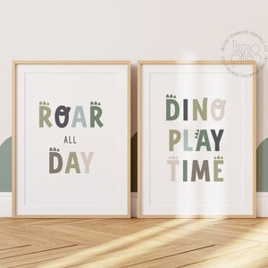 Op de afbeelding: Twee ingelijste prints met een witte achtergrond en kleurrijke tekst. De linker print zegt "Roar All Day" in groene, bruine en beige letters. De rechter print zegt "Dino Play Time" in groene, bruine en beige letters.