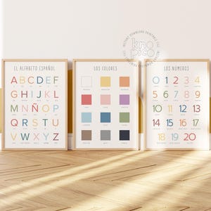 May include: Three framed educational prints. The left print displays the Spanish alphabet in colorful letters. The middle print shows color swatches. The right print features numbers 0-20. All prints have a light wood frame.