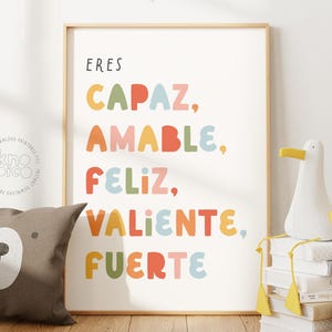 Könnte beinhalten: Ein gerahmter Druck mit den Worten "ERES CAPAZ, AMABLE, FELIZ, VALIENTE, FUERTE" in bunten Buchstaben. Ein braunes Bärenkissen und eine weiße Möwenfigur befinden sich im Vordergrund. Der Druck ist ein digitaler Download.