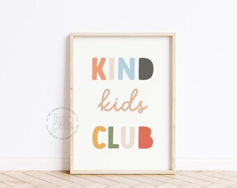 May include: A framed print with the words "KIND kids CLUB" in colorful, playful lettering. The word "KIND" is in orange, blue, and gray. "kids" is in a cursive font, and "CLUB" is in yellow, green, and red. The print has a light wood frame.
