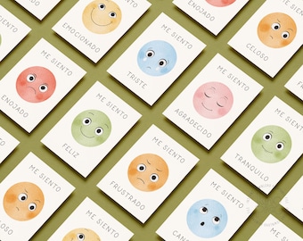 May include: Cards with watercolor illustrations of smiley faces, each representing a different emotion. The cards have text in Spanish, such as "Enojado" (angry) and "Feliz" (happy). The background is a light green color.