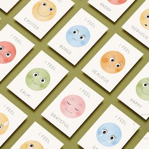 May include: Cards with watercolor illustrations of faces expressing emotions like angry, happy, and sad. Each card has the phrase "I FEEL" above the emotion. The cards are on a green background.