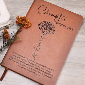 May include: A brown leather journal with the words "Chapter TWENTY-FIVE" in black script. A floral brain design and the name "Elizabeth" are also featured. The journal includes an inspirational quote.