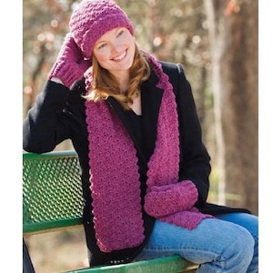 May include: A pink crocheted hat, scarf, and mittens set. The hat is a slouchy beanie style with a textured stitch. The scarf is long and rectangular with a scalloped edge. The mittens are fingerless and have a textured stitch.