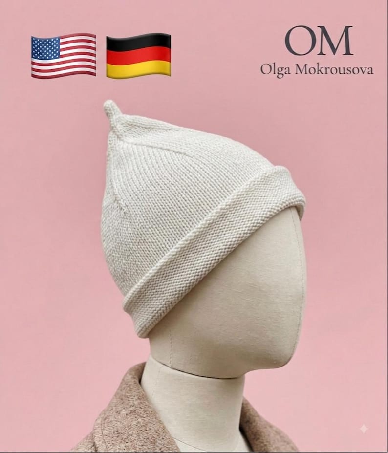 Puede incluir: Un gorro de punto color crema con una parte superior puntiaguda y un borde doblado. El gorro se muestra sobre una cabeza de maniqu&iacute;. El texto en la esquina superior derecha dice OM Olga Mokrousova, junto a las banderas de EE. UU. y Alemania.