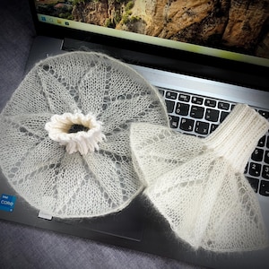 May include: A pair of off-white, sheer, mohair-style knitted accessories. One piece is a circular, lace-patterned collar with a ribbed center opening, and the other is a flared, bell-shaped cuff featuring a ribbed wrist section and delicate knit.