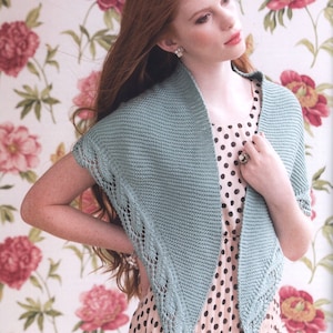 Puede incluir: Un chal de punto azul claro con un delicado patrón de encaje en los bordes. El chal está drapeado sobre los hombros de una persona que lleva un vestido de lunares.