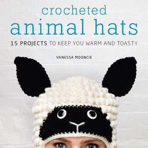 Pode incluir: Capa do livro "Crocheted animal hats" com um chapéu de ovelha de crochê branco e preto com grandes olhos pretos. O título do livro é "Crocheted animal hats" e o subtítulo é "15 projetos para mantê-lo aquecido e aconchegante". O nome do autor é Vanessa Mooncie.