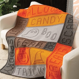 May include: A crocheted blanket with a patchwork design featuring various Halloween-themed words and images, including "Trick or Treat", "Boo", "Pumpkin", and "Candy".