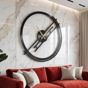 Puede incluir: Un gran reloj de pared circular con marco negro y manecillas doradas, que presenta un diseño geométrico con líneas paralelas que se extienden desde el centro. El reloj está montado en una pared de mármol blanco sobre un sofá de terciopelo rojo.