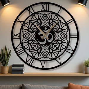 Pode incluir: Um relógio de parede redondo preto com algarismos romanos e um design floral decorativo. O relógio apresenta ponteiros dourados e o símbolo Om no centro. Está montado numa parede branca acima de uma prateleira de madeira.
