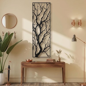 Può includere: Un pannello decorativo da parete rettangolare e alto in metallo nero, caratterizzato da un design tagliato al laser che raffigura un albero spoglio con rami intricati. L'opera è incorniciata da un bordo nero sottile e solido.