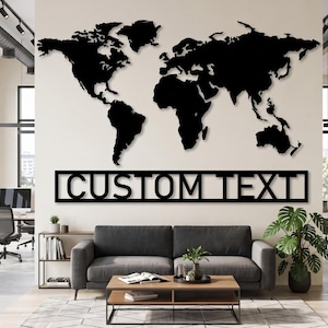 May include: A large black metal wall art piece featuring a detailed world map silhouette positioned above a rectangular frame containing the words CUSTOM TEXT in bold, capital letters. The design is flat, monochromatic, and minimalist in style.