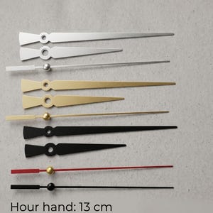 May include: Assortment of clock hands in silver, gold, black, and red. The hour hand is 5.1 inches long, and the minute hand is 7.1 inches long. The hands have a variety of shapes and include a small ball or circle at the base.
