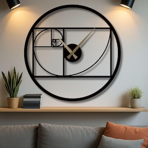 May include: A black metal wall clock with a geometric design, featuring a circular frame and a rectangular inner structure. The clock hands are gold, and the design incorporates the Fibonacci sequence. The clock is mounted on a white wall.