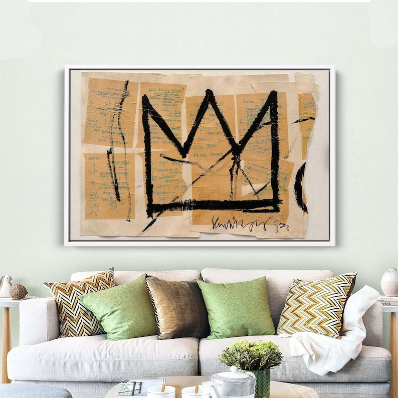 Puede incluir: Impresi&oacute;n art&iacute;stica abstracta con un dise&ntilde;o de corona negra sobre un fondo de fragmentos de papel beige con notas manuscritas. La obra de arte est&aacute; enmarcada en un borde blanco. La pieza se exhibe sobre un sof&aacute; blanco.