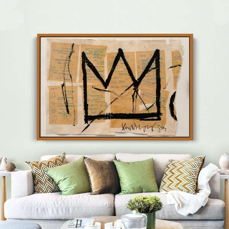 Puede incluir: Impresi&oacute;n art&iacute;stica abstracta con un dise&ntilde;o de corona negra sobre un fondo de fragmentos de papel rasgados con texto manuscrito. La obra de arte est&aacute; enmarcada en un marco de madera marr&oacute;n. La pieza se exhibe sobre un sof&aacute; blanco con cojines verdes y estampados.