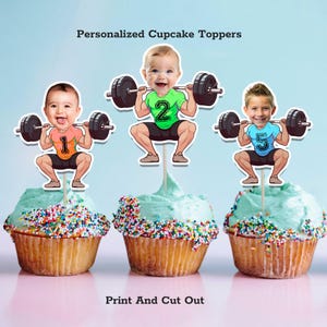 Puede incluir: Tres cupcakes con glaseado azul y chispas de colores. Cada cupcake tiene un adorno personalizado de un niño levantando pesas. Los adornos tienen el texto "Personalized Cupcake Toppers" y "Print And Cut Out".