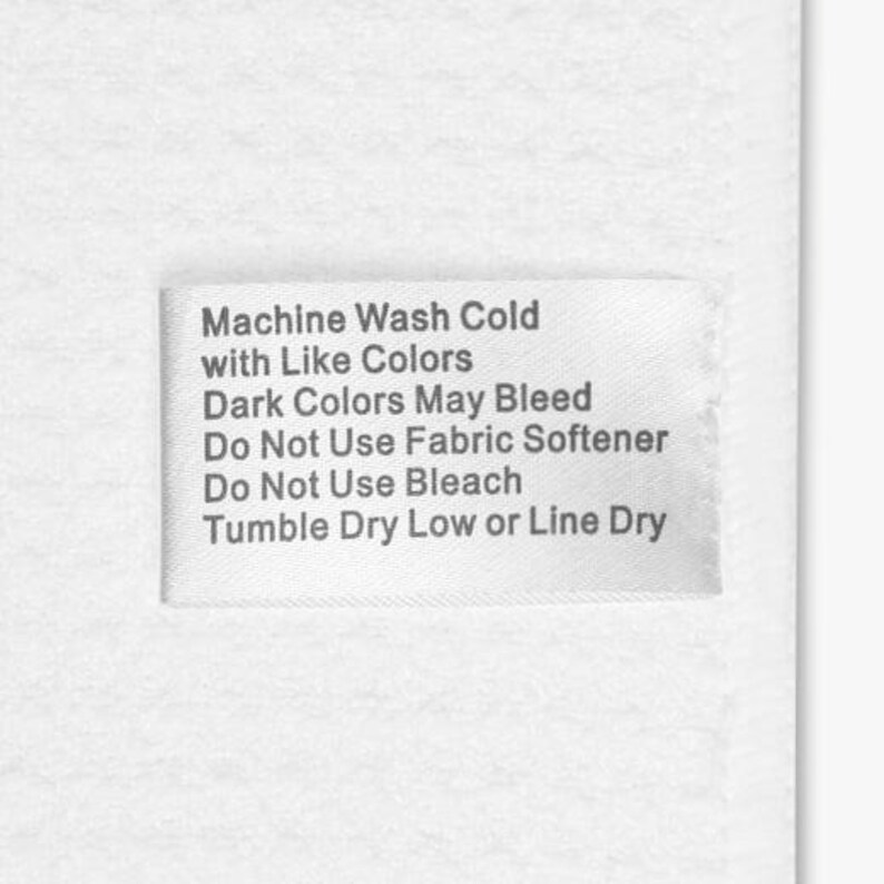 Puede incluir: Una etiqueta de tela blanca con texto negro. El texto dice: Machine Wash Cold with Like Colors, Dark Colors May Bleed, Do Not Use Fabric Softener, Do Not Use Bleach, Tumble Dry Low or Line Dry.