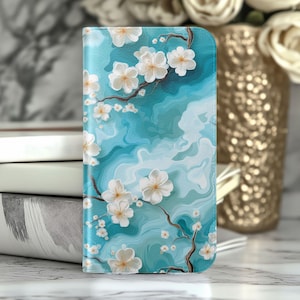 May include: A rectangular phone case featuring a vibrant turquoise and light blue marbled background with dark brown branches and white cherry blossom flowers scattered across the surface. The design covers the entire front of the phone case.