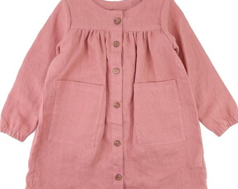 May include: A long-sleeved, pink linen dress with a button-up front and two patch pockets. The dress has a gathered bodice and a relaxed fit.