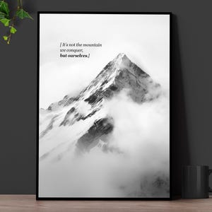 Puede incluir: Fotografía en blanco y negro de un pico de montaña con nubes. La cita "No es la montaña la que conquistamos, ¡sino nosotros mismos!" está impresa en la imagen.