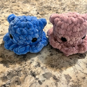 Puede incluir: Dos peluches de ganchillo con forma de pulpo. Uno es azul y el otro es rosa.