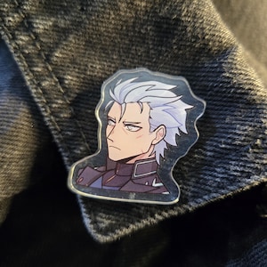 May include: A clear acrylic pin featuring a stern-faced anime character with white hair and a dark outfit. The pin is a portrait of the character, with a detailed design and a glossy finish. The pin is attached to a dark denim jacket.