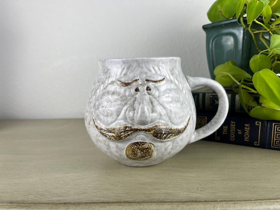 Hand-sculpted 1970s-style character face mug — every lump, grimace, and glaze drip is one-of-a-kind studio pottery you genuinely cannot find at Target.