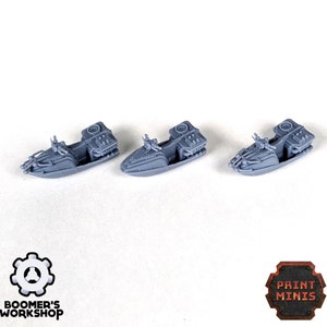 May include: Three gray 3D printed miniature hovercrafts. The hovercrafts have a rounded body, a raised cockpit, and a rear engine compartment. The hovercrafts are arranged in a row on a white surface.