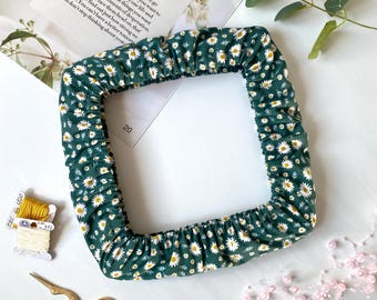 Puede incluir: Un artículo de tela verde cuadrado con un estampado de margaritas blancas. El texto "SUNDAY GIRL" es visible en el fondo. También hay tijeras doradas, hilo y cuentas rosas.