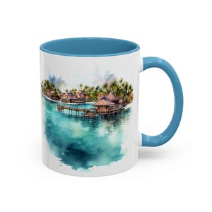 Può includere: Tazza in ceramica bianca con interno e manico blu. La tazza presenta un'illustrazione ad acquerello di bungalow sull'acqua, palme e acqua turchese. Il design avvolge la tazza.