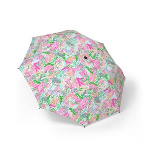 May include: An open umbrella with a bright floral design. The pattern includes pink, green, and orange flowers and leaves on a pale blue backdrop. This umbrella is a fashionable accessory for both sunny and rainy weather.