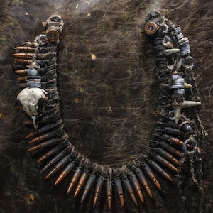 Könnte beinhalten: Eine Halskette aus Kugeln, Knochen und Metallbeschlägen. Die Halskette ist braun und schwarz und hat einen rustikalen Look.
