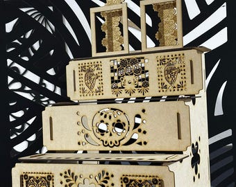 May include: A multi-tiered, wooden display stand with intricate laser-cut designs. The stand features a Day of the Dead theme, with skull and floral motifs. The natural wood color contrasts with the black and white patterned background.