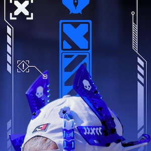 May include: White baseball cap with blue, transparent, angular attachments. The cap features a skull design and a logo. The background is a gradient of blue. The cap has a gray adjustable strap.